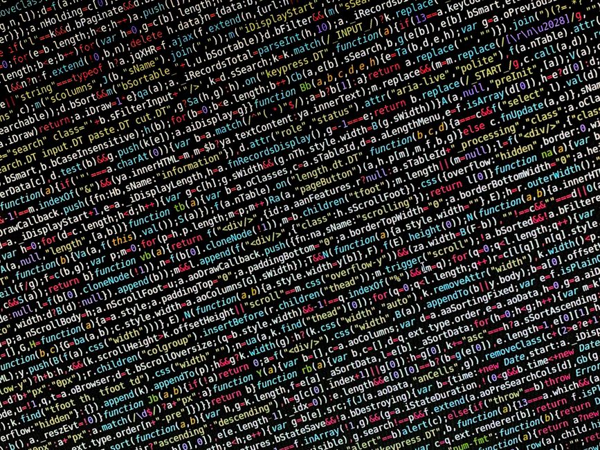 Close-up view of a computer screen displaying lines of colorful HTML and CSS code on a dark background, indicating digital programming or web development activities. The screen shows a mixture of red,